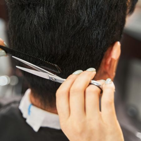 Barber keeping comb near man hair while trimming