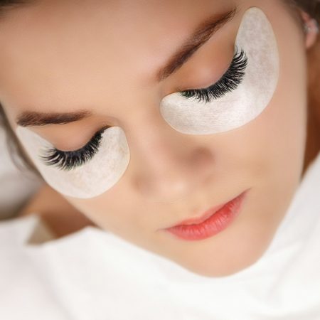 Eyelash Extension Procedure. Woman Eye with Long Eyelashes. Close up, selective focus