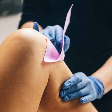 Waxing - Beautician Removing Unwanted Hair from Female Leg with Wax Strips